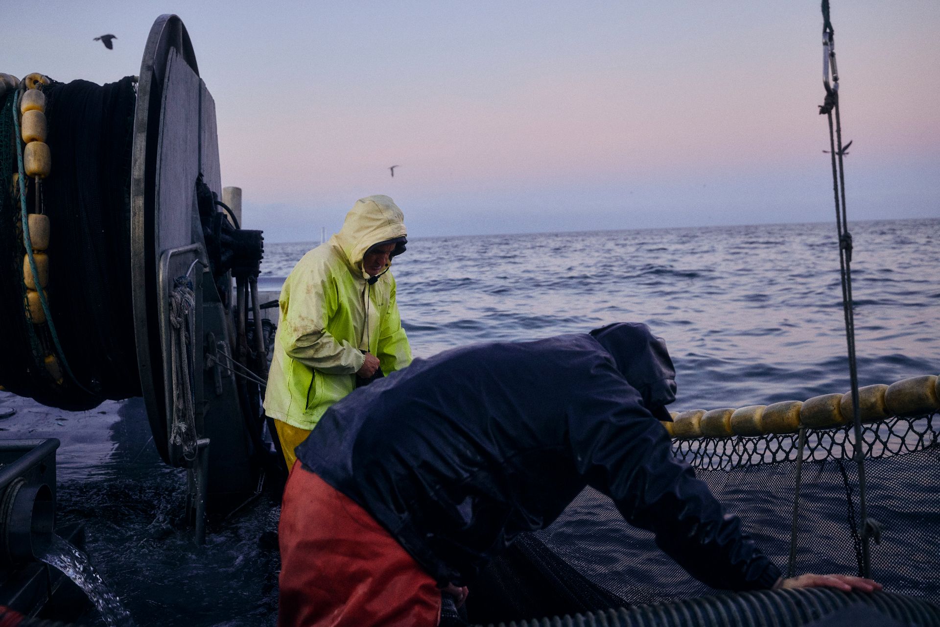 Fisherman in foul-weather gear working on a boat deck at dawn in The Purveyors, an original docuseries